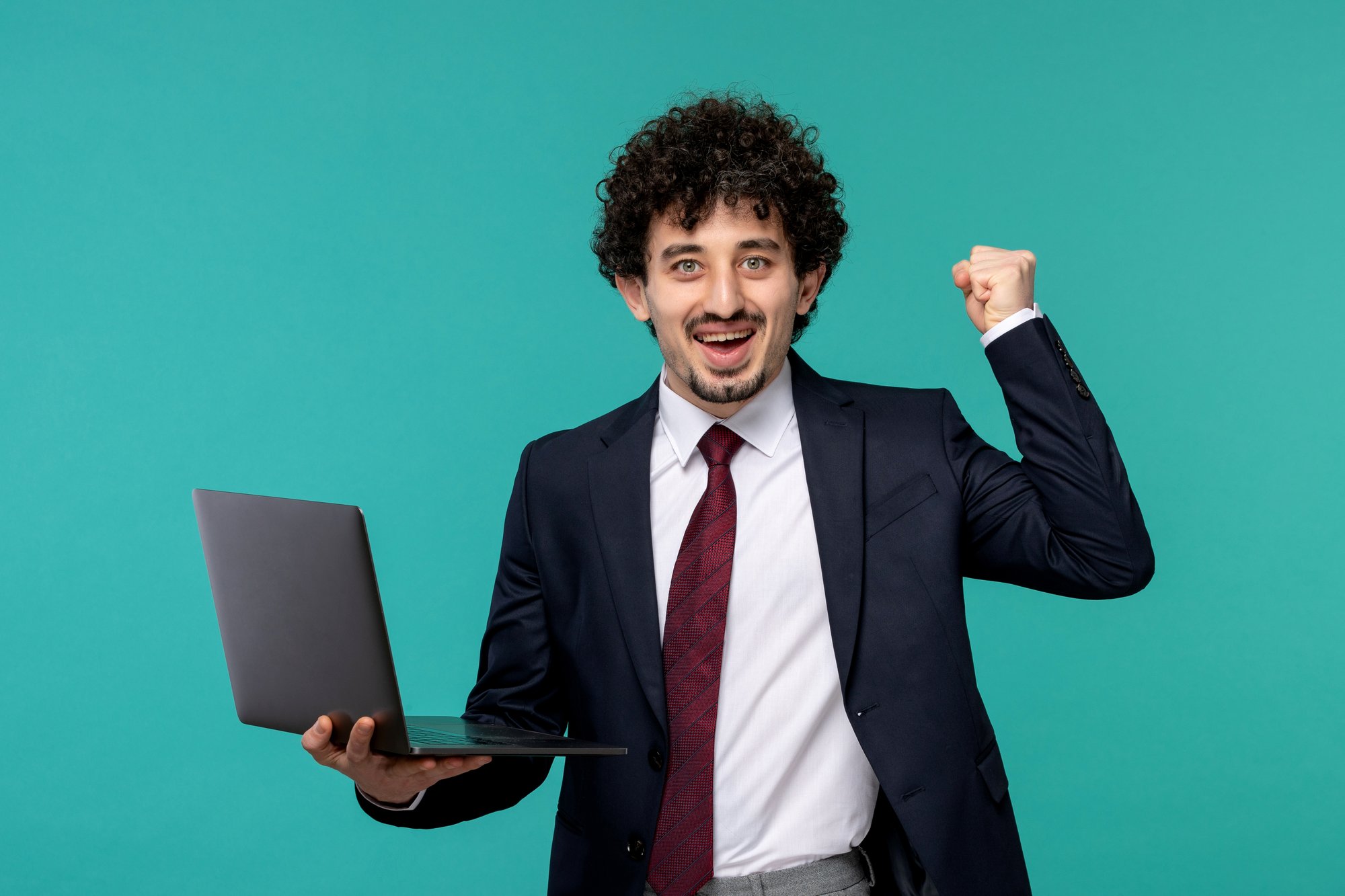 business-man-curly-cute-handsome-guy-black-suit-red-tie-holding-laptop-excited